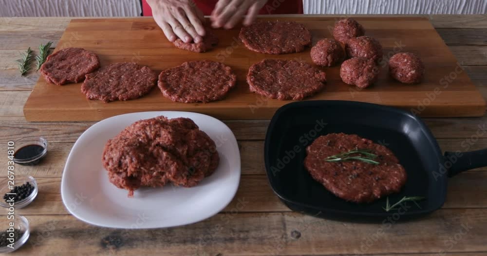 Cooking at home, burger preparing. Hands making meatball, and tapping it to thin minced beef steak, close-up Cooking at home, burger preparing. Hands making meatball, and tapping it to thin minced beef steak, close-up
