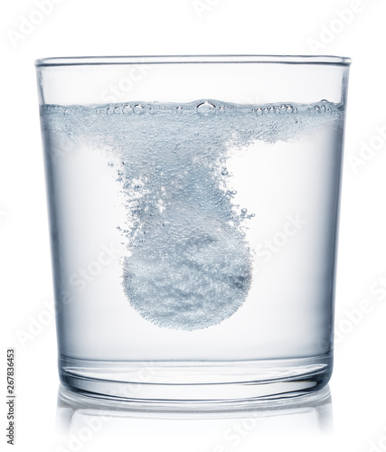 Effervescent tablet dissolving in a glass of water. Clipping path.