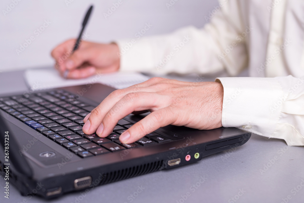 Businessman write in paper documents over the laptop keyboards. Businessman write in paper documents over the laptop keyboards.
