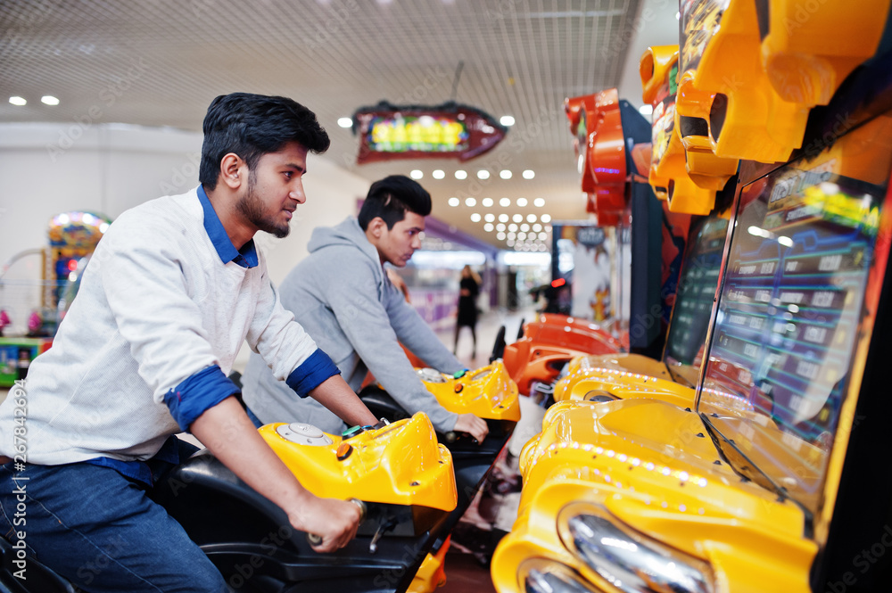 Two asian guys compete on speed rider arcade game motorcycle racing simulator machine. Two asian guys compete on speed rider arcade game motorcycle racing simulator machine.