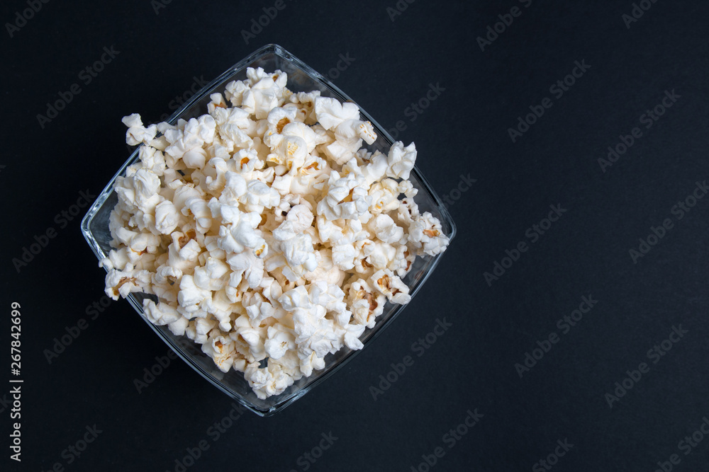 Popcorn in a glass bowl on a black background. Top view with copy space.