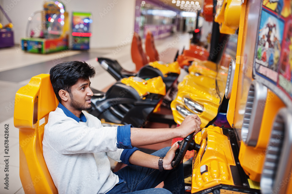 Asian guy compete on speed rider arcade game racing simulator machine. Asian guy compete on speed rider arcade game racing simulator machine.
