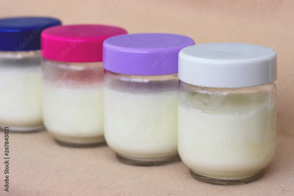 Portion of fresh natural homemade organic yogurt in a glass bowl with colored covers Portion of fresh natural homemade organic yogurt in a glass bowl with colored covers