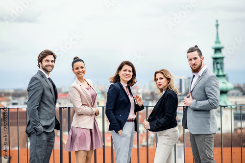A group of joyful businesspeople standing outdoors on roof terrace in city.