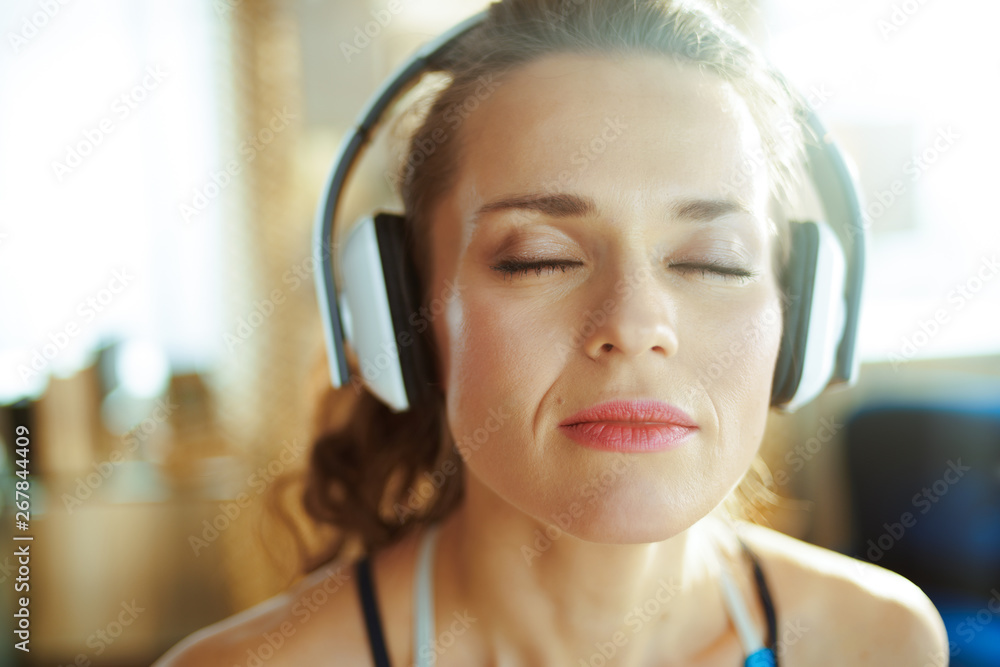 sports woman listening to music with headphones in modern house