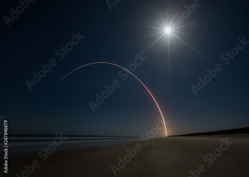Delta 4 rocket launch into full moon lit sky as seen from Canaveral National Seashore in Floirda