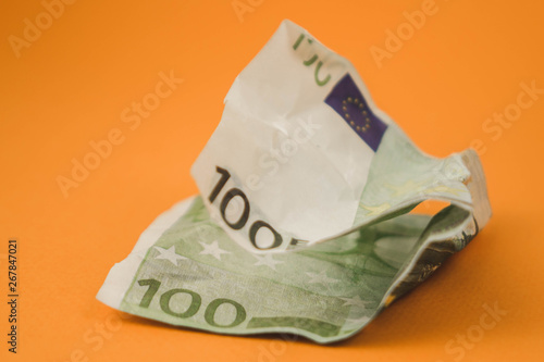 crumpled hundred euro lying on orange background photo