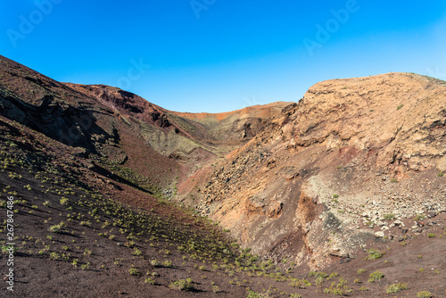 Timanfaya National Park, mountains of fire at Lanzarote, Canary Islands, Spain. Unique panoramic view of spectacular corrosioned lava ground layers s of a huge volcano cone.