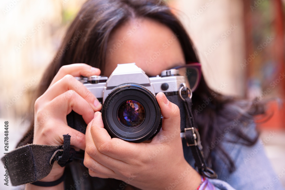 Retrato del rostro de mujer joven sujetando con sus manos una preciosa cámara de fotos analógica en la calle Retrato del rostro de mujer joven sujetando con sus manos una preciosa cámara de fotos analógica en la calle