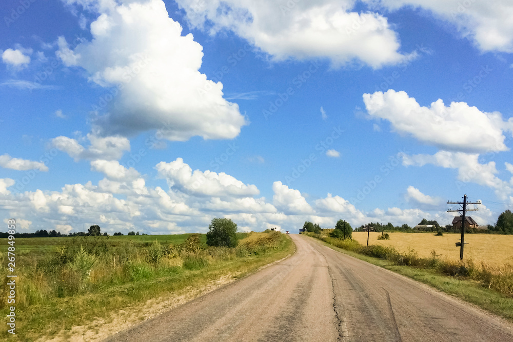 Empty asphalt road, rural fields and blue sky with white clouds. Perspective, background