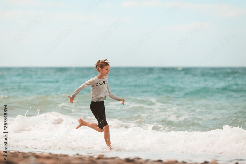 Young girl running through the waves at the beach