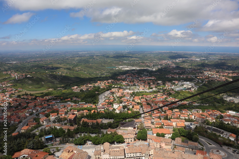 panoramic view from top of Fortress Guaita on Mount Titano on city San Marino ,Italy with beautiful blue sky with clouds on sunny day. View towards the sea and over the San Marino villages and Rimini,