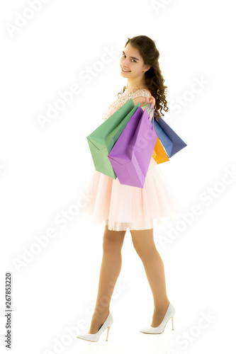 Teenager girl shopping in a store with large paper bags.