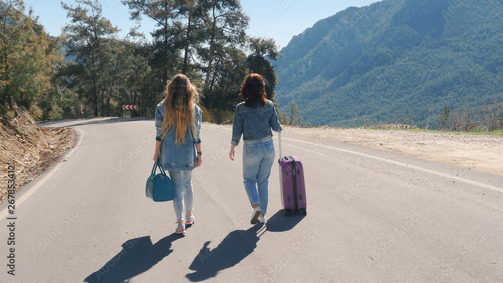 Two young girls walking down the road with beautiful nature landscape Two young girls walking down the road with beautiful nature landscape