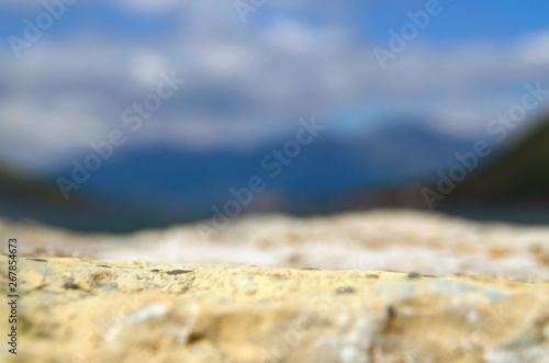Summer blurred background. Stone, sand, mountains, sea and sky.