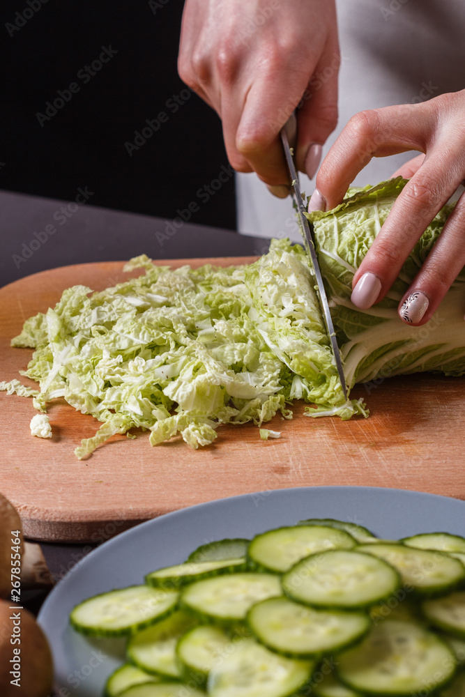 A young woman in a gray apron cuts chinese cabbage A young woman in a gray apron cuts chinese cabbage