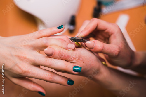 A woman treats the cuticles on the fingers with nail clippers. Salon procedures at home. close-up