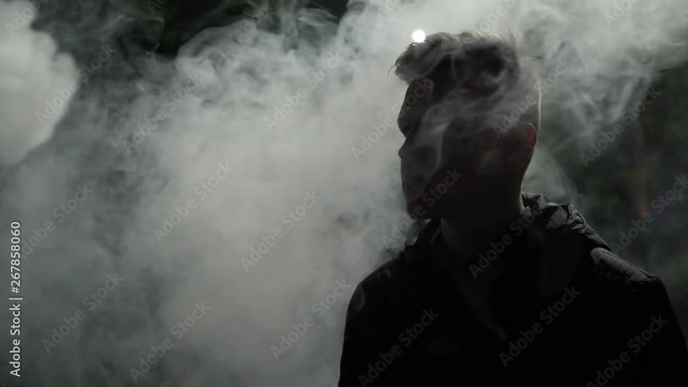 urban silhouette of pensive young man in the smoke on the street at night urban silhouette of pensive young man in the smoke on the street at night