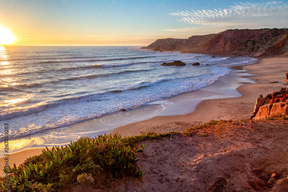 Sunset at Praia do Amado in the Costa Vicentina natural park at the Atlantic Ocean at the Algarve, Portugal.