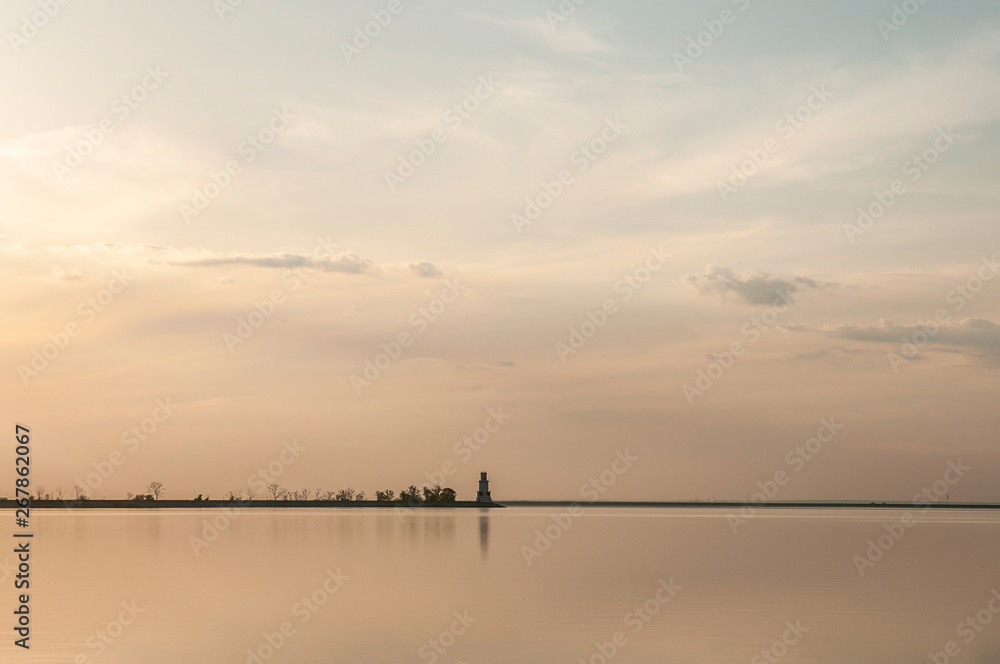 distant lighthouse on the dam at sunset