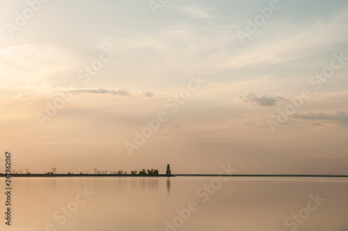 distant lighthouse on the dam at sunset © Roman