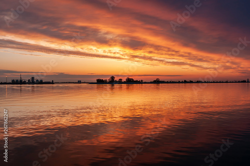 dark orange sunset spring evening on the river or reservoir © Roman