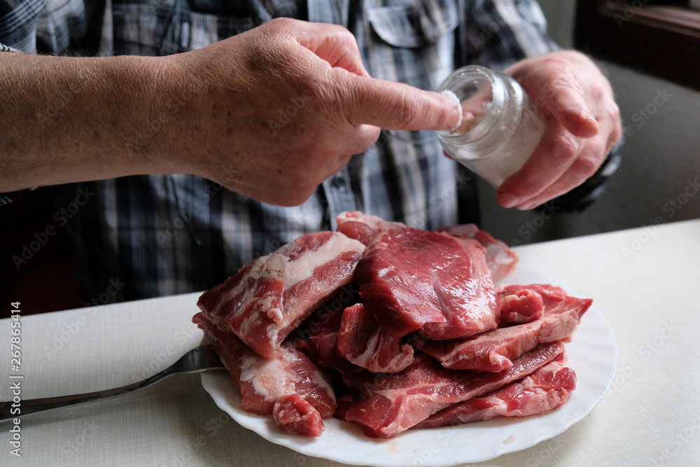Salting raw beef meat on a plate