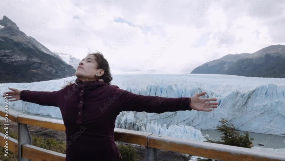 Free young woman carefree and happy with open arms on the background glacier landscape. Perito Moreno Glacier, Patagonia. Slow motion Free young woman carefree and happy with open arms on the background glacier landscape. Perito Moreno Glacier, Patagonia. Slow motion