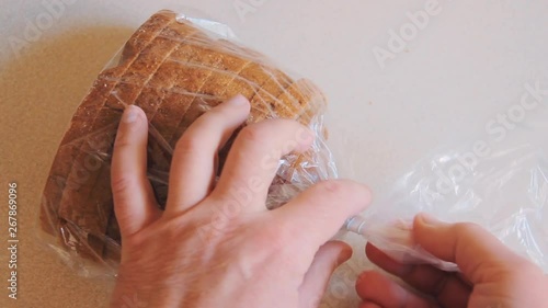 Male hands open plastic bag with bread on the table. The packaging is closed on a latch.