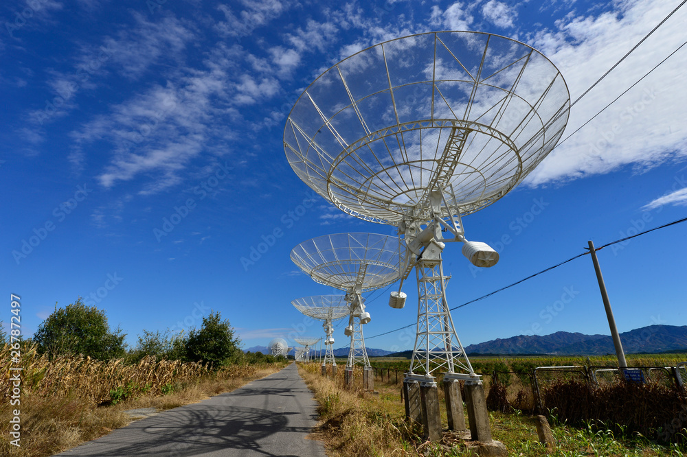 Array of satellite dishes or radio antennas against sky. Space o