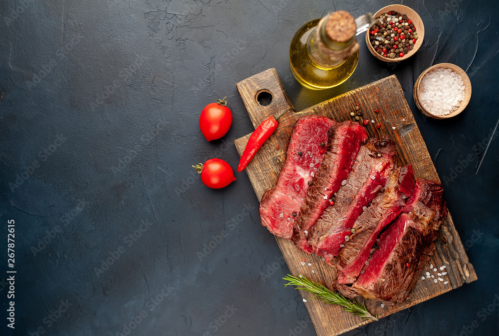 Grilled rib eye beef steak with herbs and spices on a stone background with copy space for your text