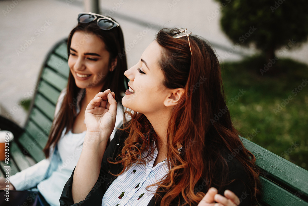 Close up portrait of a amazing plus size woman with red hair storytelling something captivant to her girlfriend while sitting on a bench. Close up portrait of a amazing plus size woman with red hair storytelling something captivant to her girlfriend while sitting on a bench.