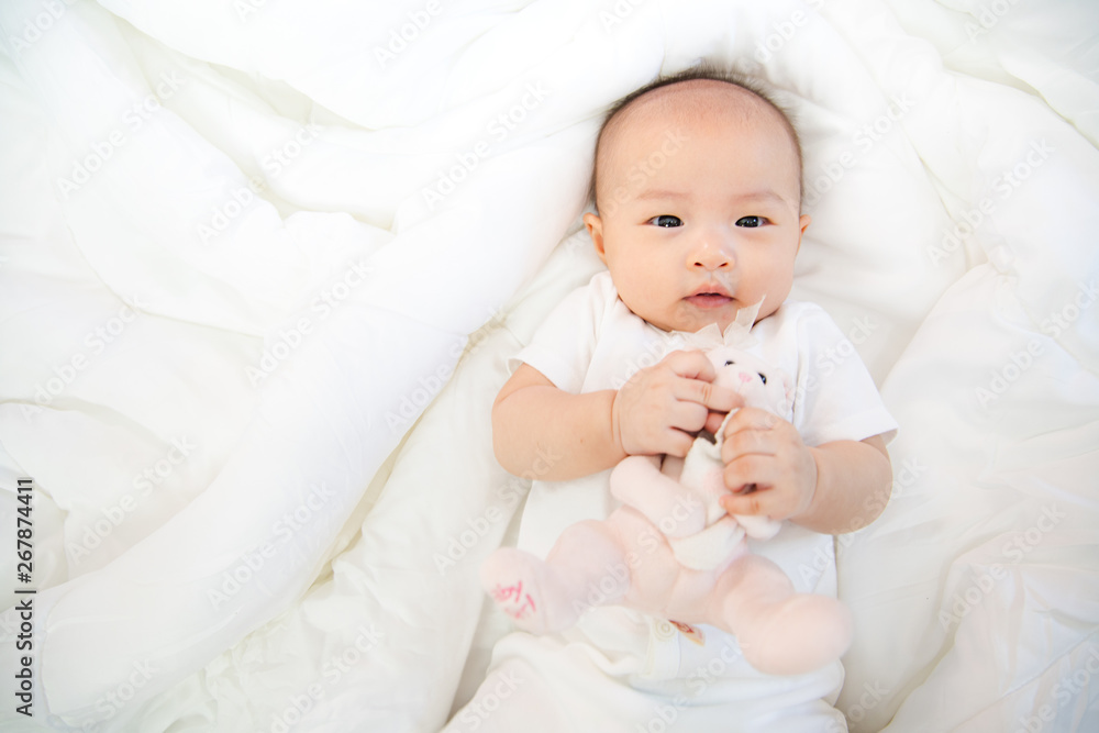 Asian baby happy in the room.Asian baby girl lying down on bed . Asian baby happy in the room.Asian baby girl lying down on bed .