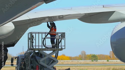 Airport airplane crew refueling aircraft on airline by technical staff maintenance ground. Preparing airplane for departure. repair of aircraft service worker use fuel hose on aircraft wing, on stairs