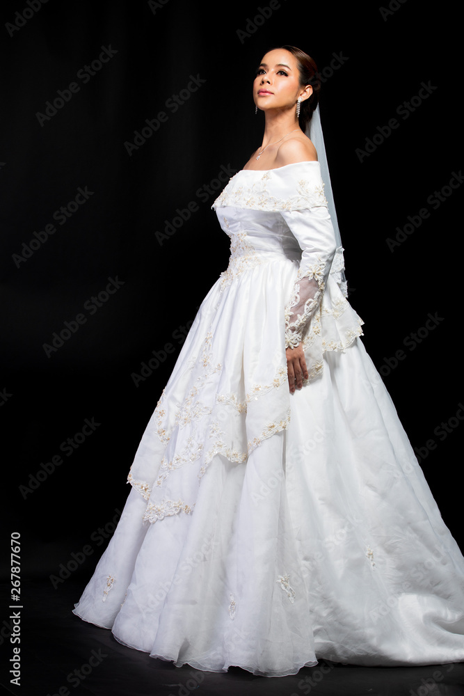 Lovely Asian Beautiful Woman bride in white wedding gown dress with lace veil, black hair, studio lighting black gradient background isolated copy space, sweet romantic soft alone bridal concept