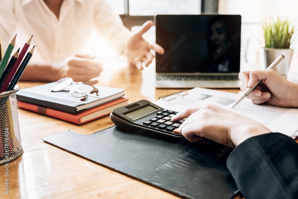 Close up Businessman and partner using calculator and laptop for calaulating finance, tax, accounting, statistics and analytic research concept