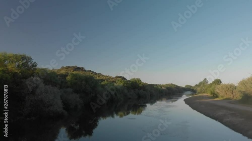 Drone shot of a calm river surrounded by trees during sunset photo