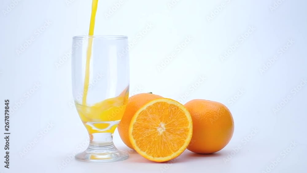 4k Slider shot of orange juice pouring into transparent glass with orange fruits on white background 4k Slider shot of orange juice pouring into transparent glass with orange fruits on white background