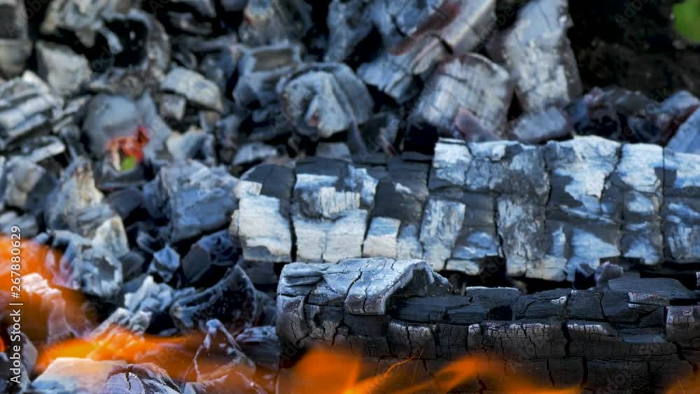 Burning wood an coals in rusty portable outdoor BBQ grill in sunny day, close up shot Burning wood an coals in rusty portable outdoor BBQ grill in sunny day, close up shot
