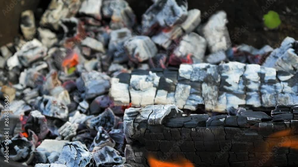 Burning wood an coals in rusty portable outdoor BBQ grill in sunny day, close up shot in slow motion Burning wood an coals in rusty portable outdoor BBQ grill in sunny day, close up shot in slow motion