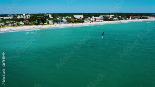 Aerial of man on hydrofoil kitesurfing along Indian Rocks beach shore in Florida.