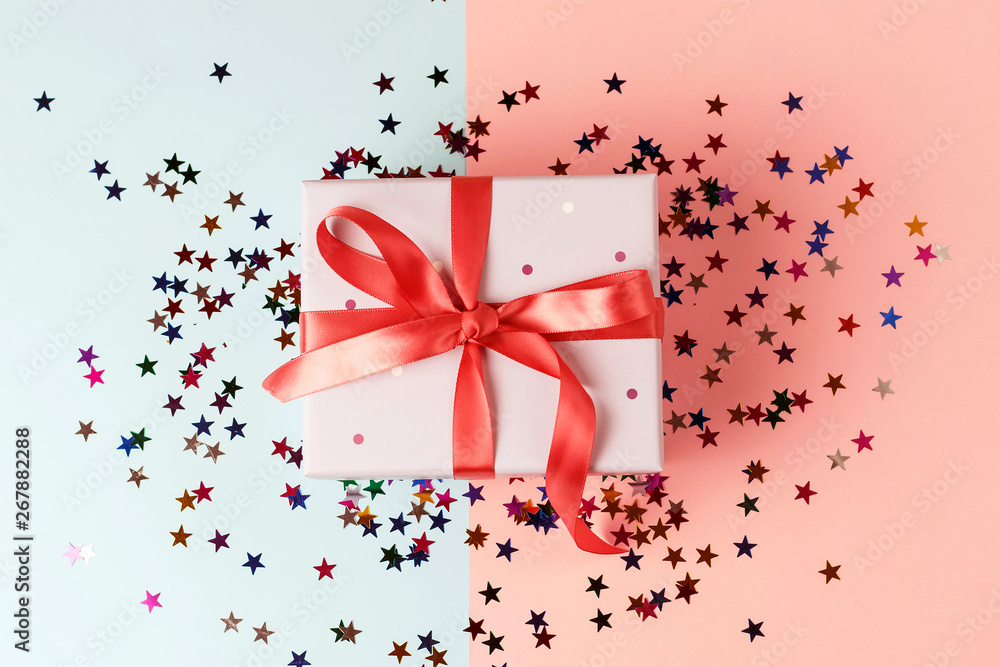 Gift box with ribbon on pink and blue background close-up, top view Gift box with ribbon on pink and blue background close-up, top view