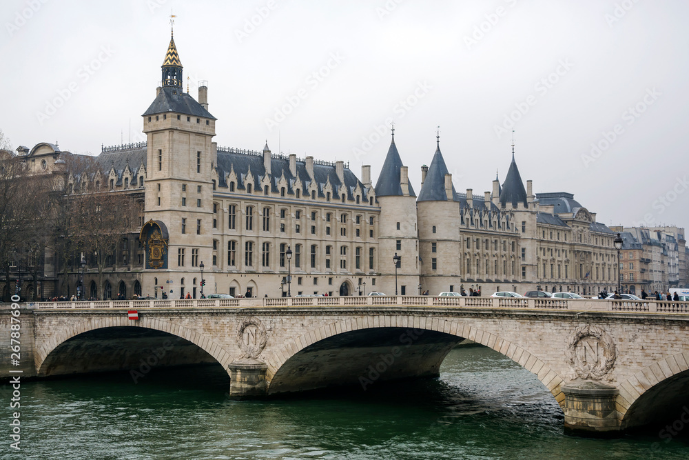 View of the Castle Conciergerie and Pont au Change over the Seine River in Paris on a cloudy winter day, France