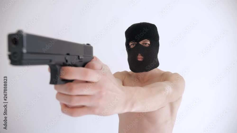Terrorist with a naked torso in balaclava aims his gun on white background Terrorist with a naked torso in balaclava aims his gun on white background