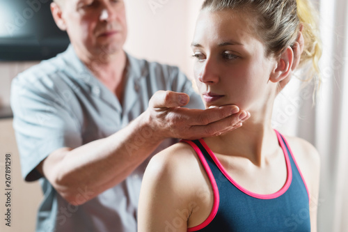 Male manual visceral therapist masseur treats a young female patient. Warm up the shoulders and neck