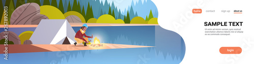 woman hiker making fire near tent camp african girl holding firewood for bonfire hiking camping concept landscape nature river forest mountains background horizontal full length copy space