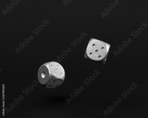 Two Rolling Silver Casino Dice on Black Background showing five and one