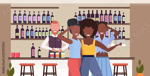 african american girls taking selfie photo on smartphone camera people relaxing in bar drinking cocktails barman serving clients modern cafe interior flat horizontal portrait