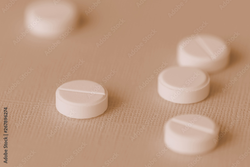 White tablets scattered on a surface close up. Brown color toned White tablets scattered on a surface close up. Brown color toned