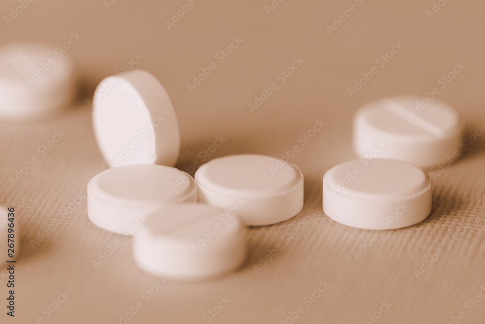 White tablets scattered on a surface close up. Brown color toned White tablets scattered on a surface close up. Brown color toned